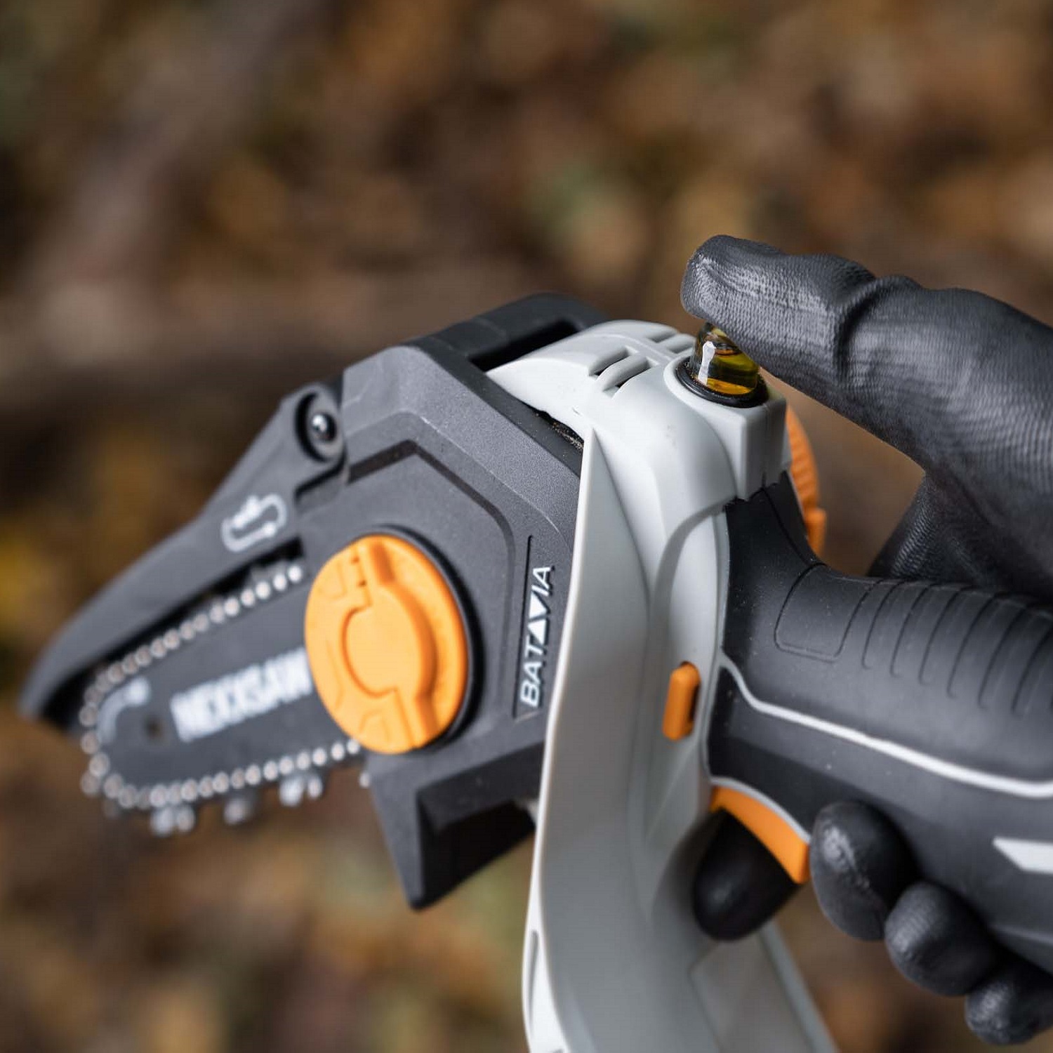 Close-up of a person holding the Batavia NEXXSAW 18V Cordless One-Handed Pruning Chainsaw with a gloved hand.