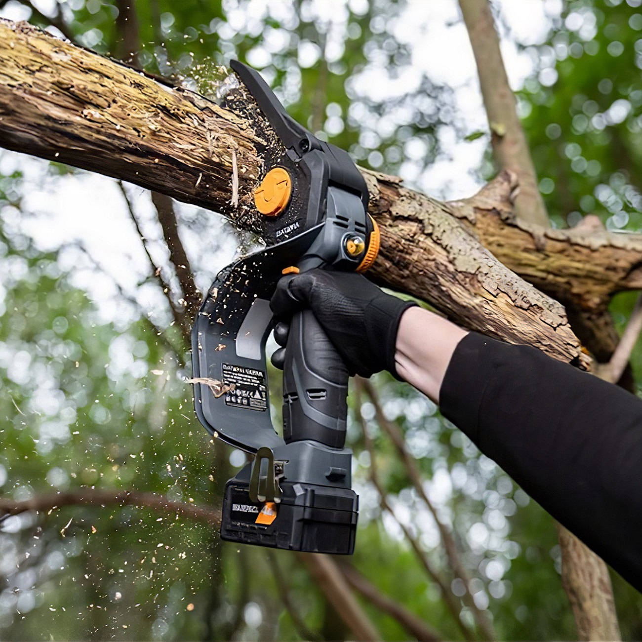 Person using a Batavia NEXXSAW 18V cordless one-handed pruning chainsaw to cut a tree branch in a forest setting.