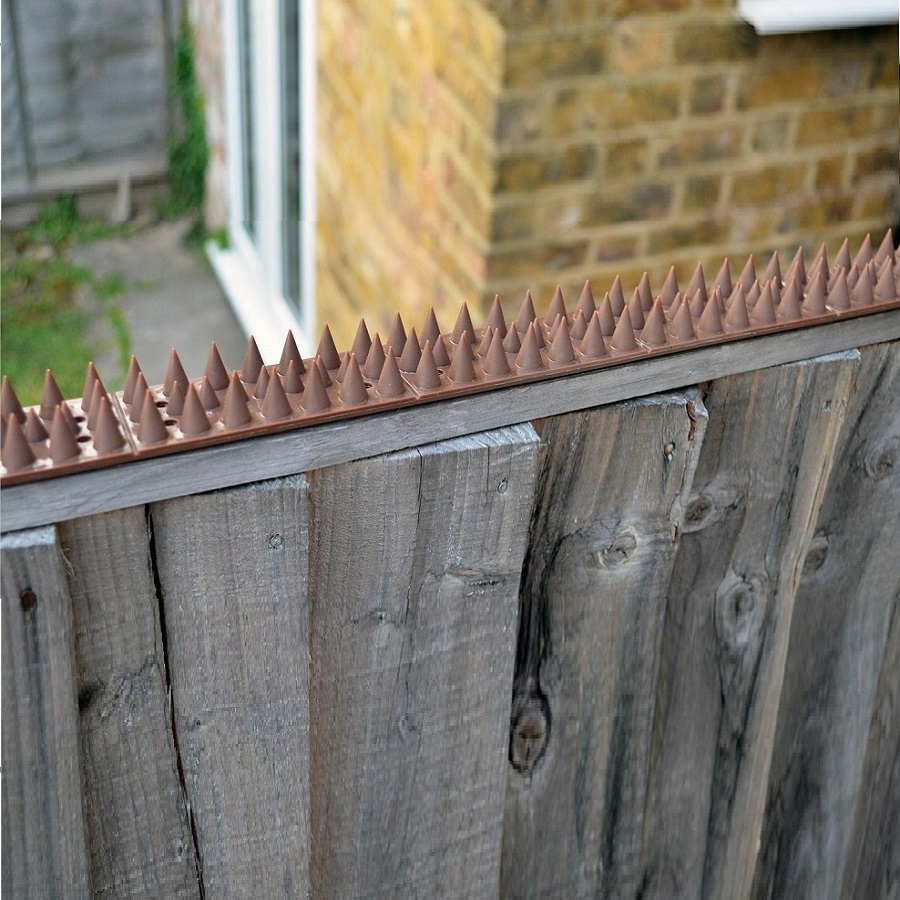Brown prickle spikes installed on a wooden fence for security.