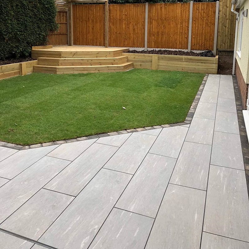 Paved garden area with light grey tiles and a wooden deck.