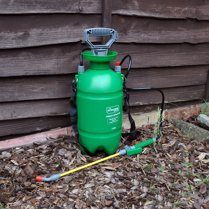 Green Kingfisher Garden Fence Pressure Sprayer with Trigger Lock 5L placed on the ground next to a wooden fence.