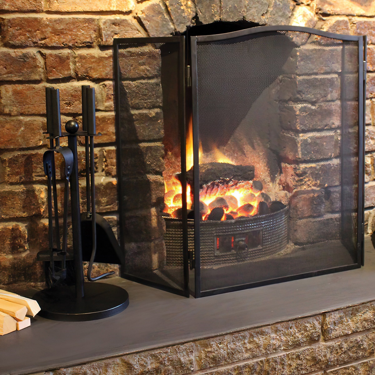 Folding fire screen in front of a lit fireplace, providing spatter protection.