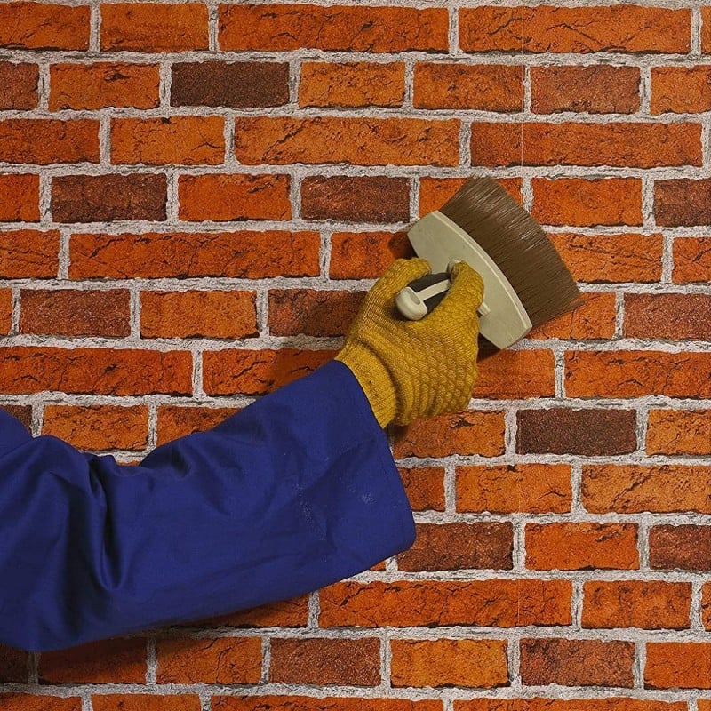 Person applying sealer to a brick wall with a brush