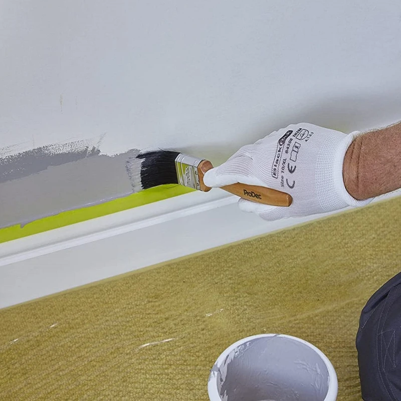 Person wearing BlackRock Lightweight Gripper Work Gloves painting a wall with a brush.