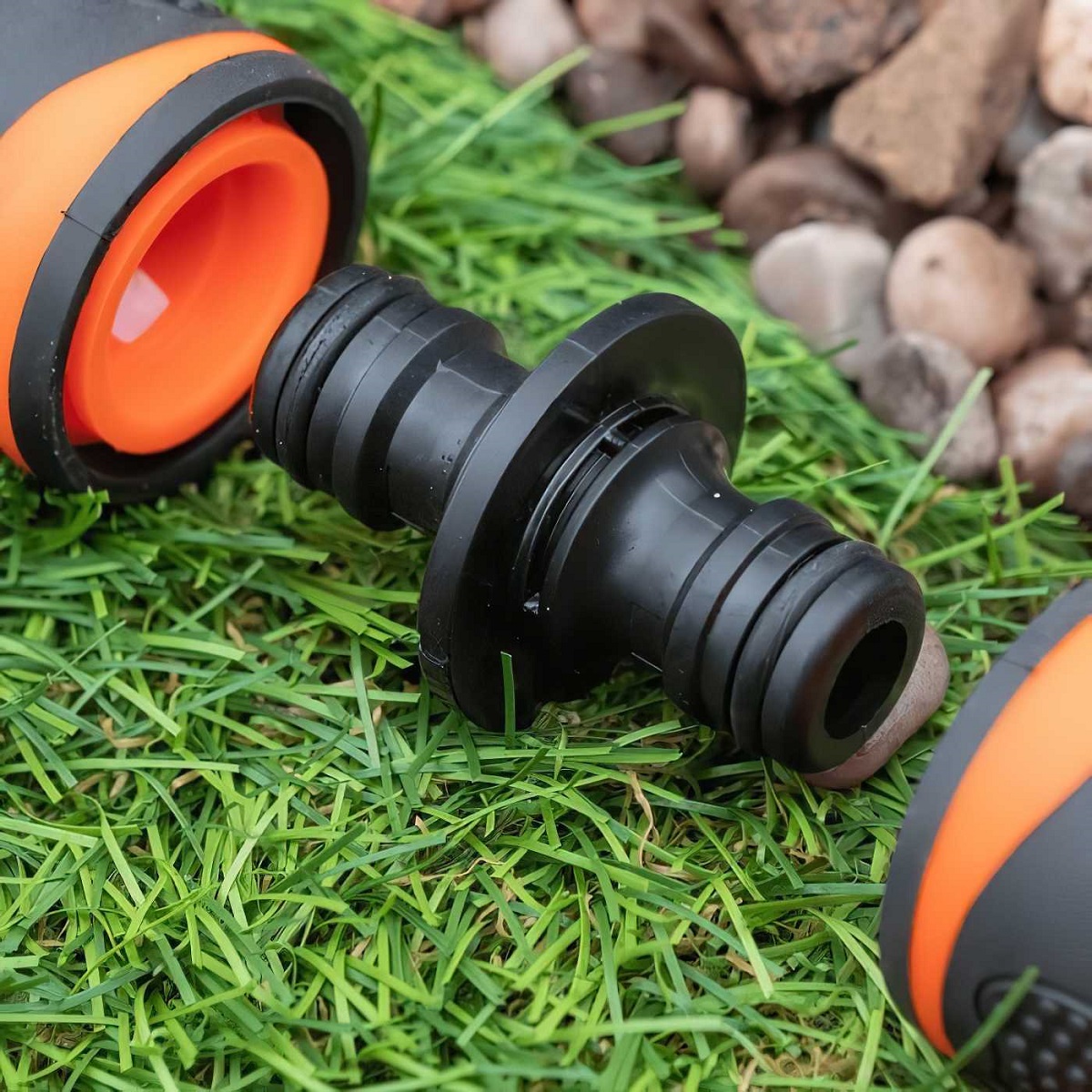 Close-up of a black double male hose pipe straight adapter joiner on grass.