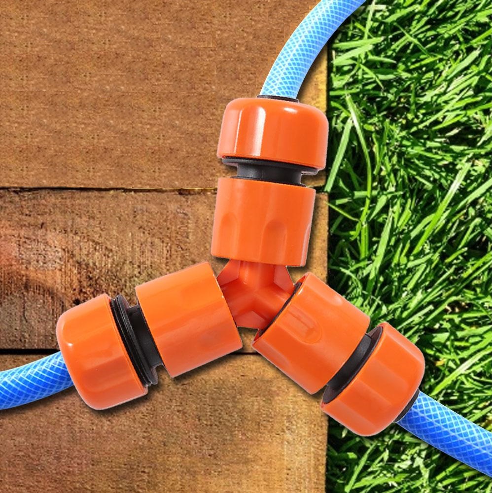 Orange 3-way hose pipe connector adapter attached to blue hoses on a wooden and grass background.