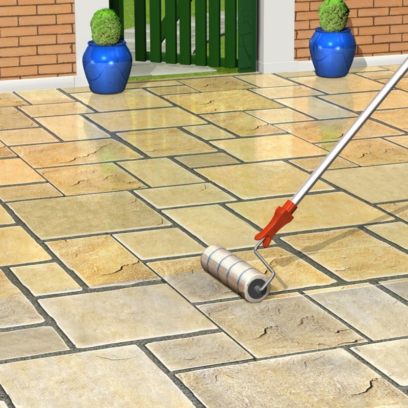 A roller applying sealer to Indian sandstone paving in a garden setting.