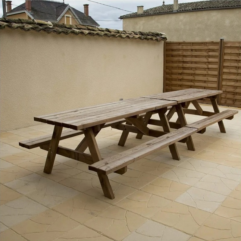 Wooden picnic table on a paved patio with a wooden fence and house in the background.