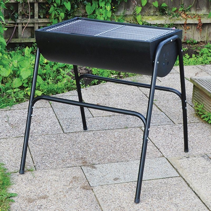 A black metal barbecue grill on a patio with paving stones and greenery in the background.