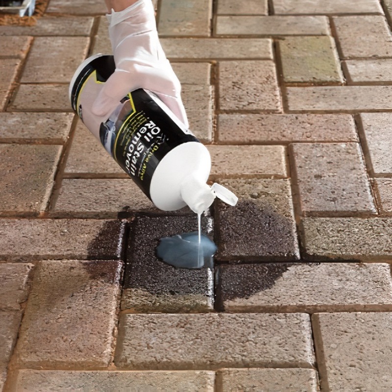 Person applying Bond It Drive Alive Oil Stain Remover on a patio surface.