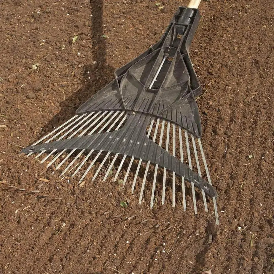 A rake on freshly prepared soil in a garden.
