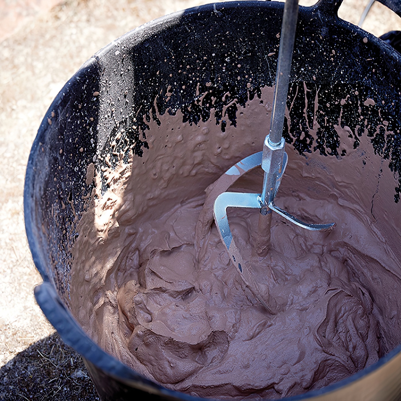 Close-up of a flexible tub with mixed material inside and a mixing tool.