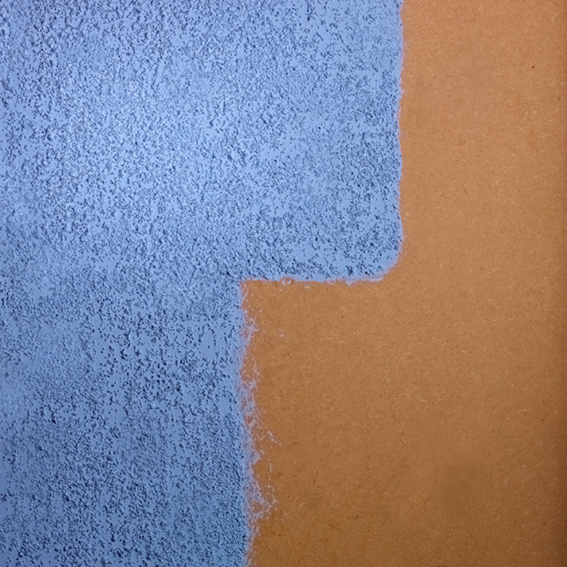 Close-up of a wall section with blue plaster coating applied over a brown surface.