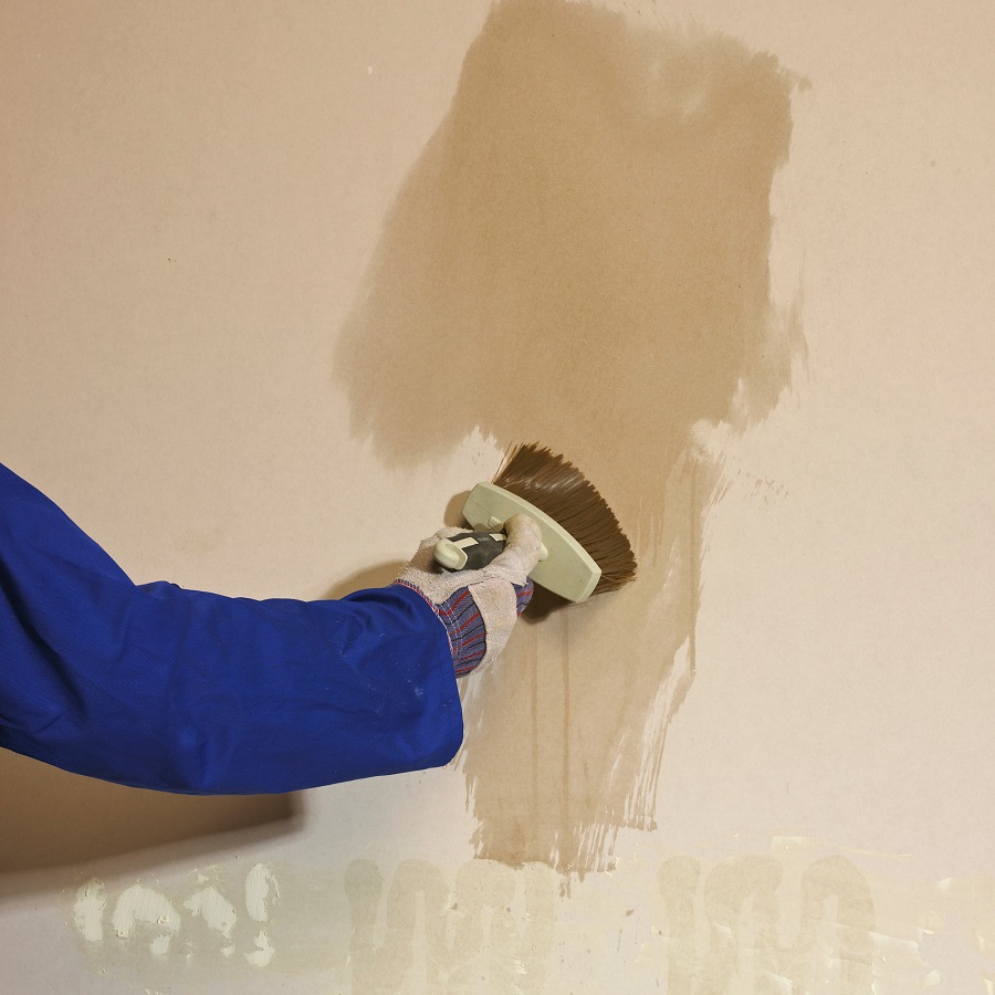 Person applying paint with a brush on a wall