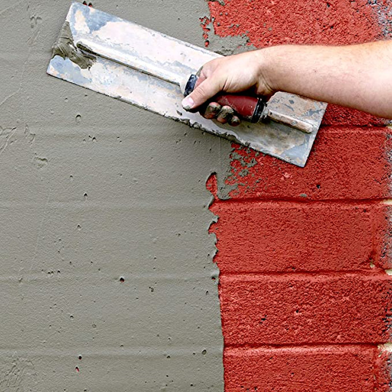 A person applying Everbuild 507 Rendagrip Extra-Grip Render Bonding Coating on a brick wall.