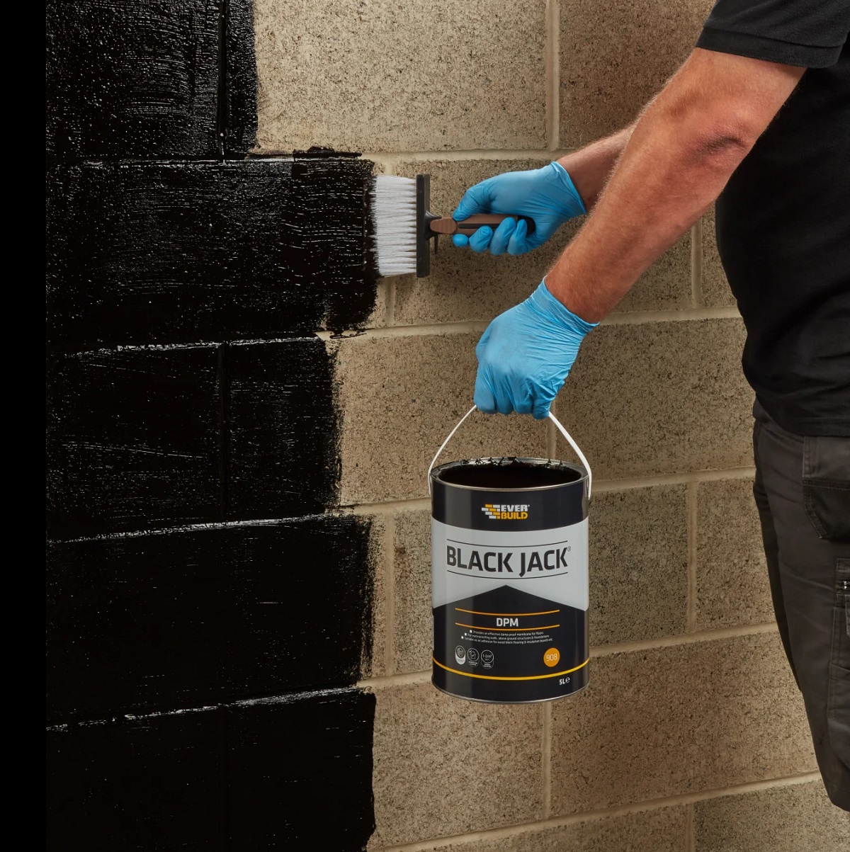 Person applying Everbuild 908 Damp Proof Membrane on a brick wall with a brush.