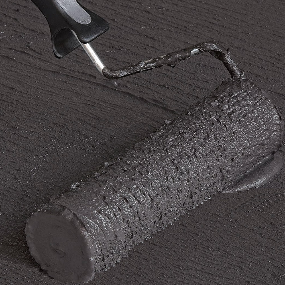 Close-up of a roller applying dark liquid membrane on a surface
