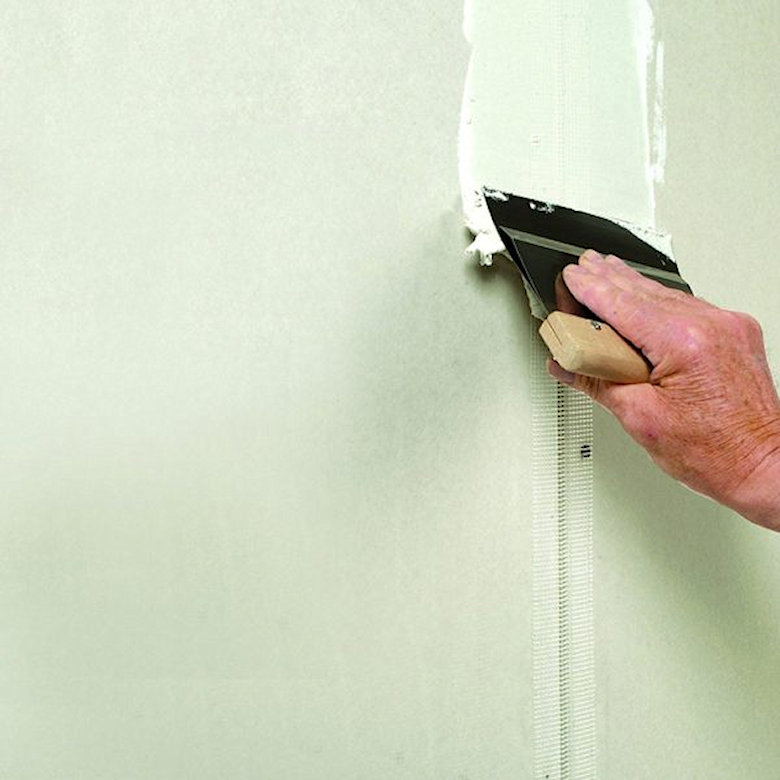 A person applying plaster to a wall with a trowel.
