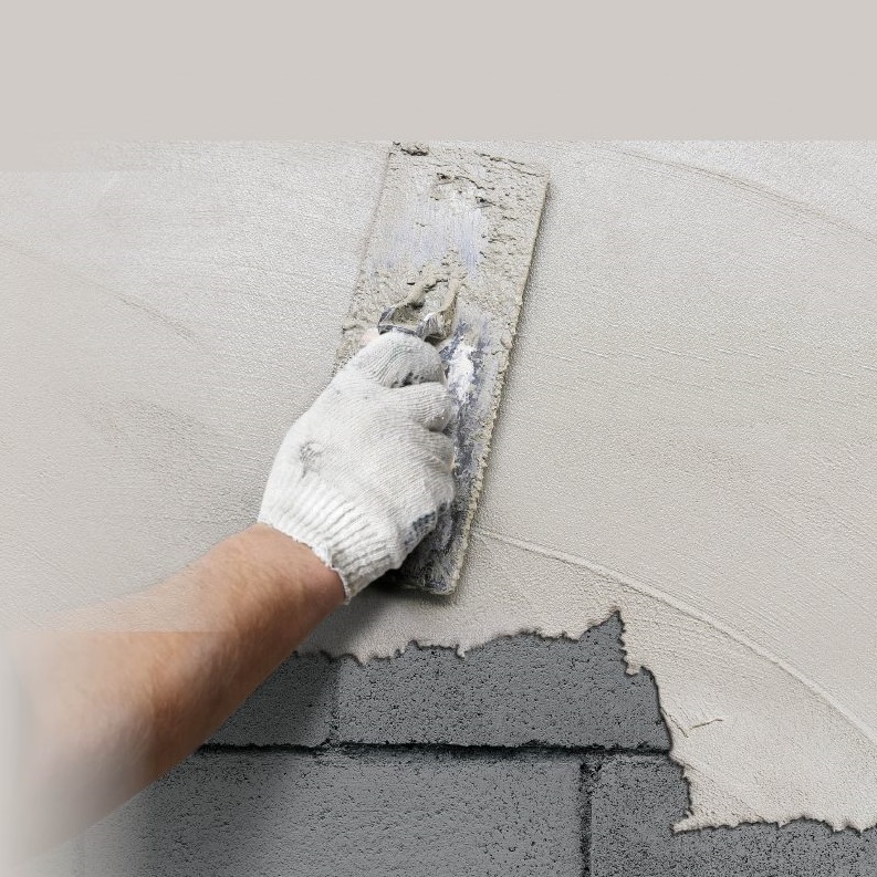 A person applying plaster to a wall with a trowel.