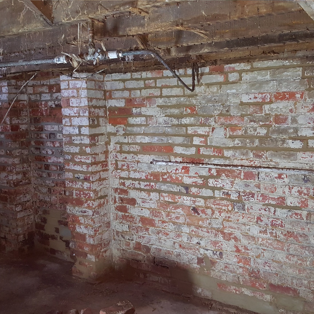 Interior view of a brick wall with signs of decay and damage, possibly affected by dry rot.