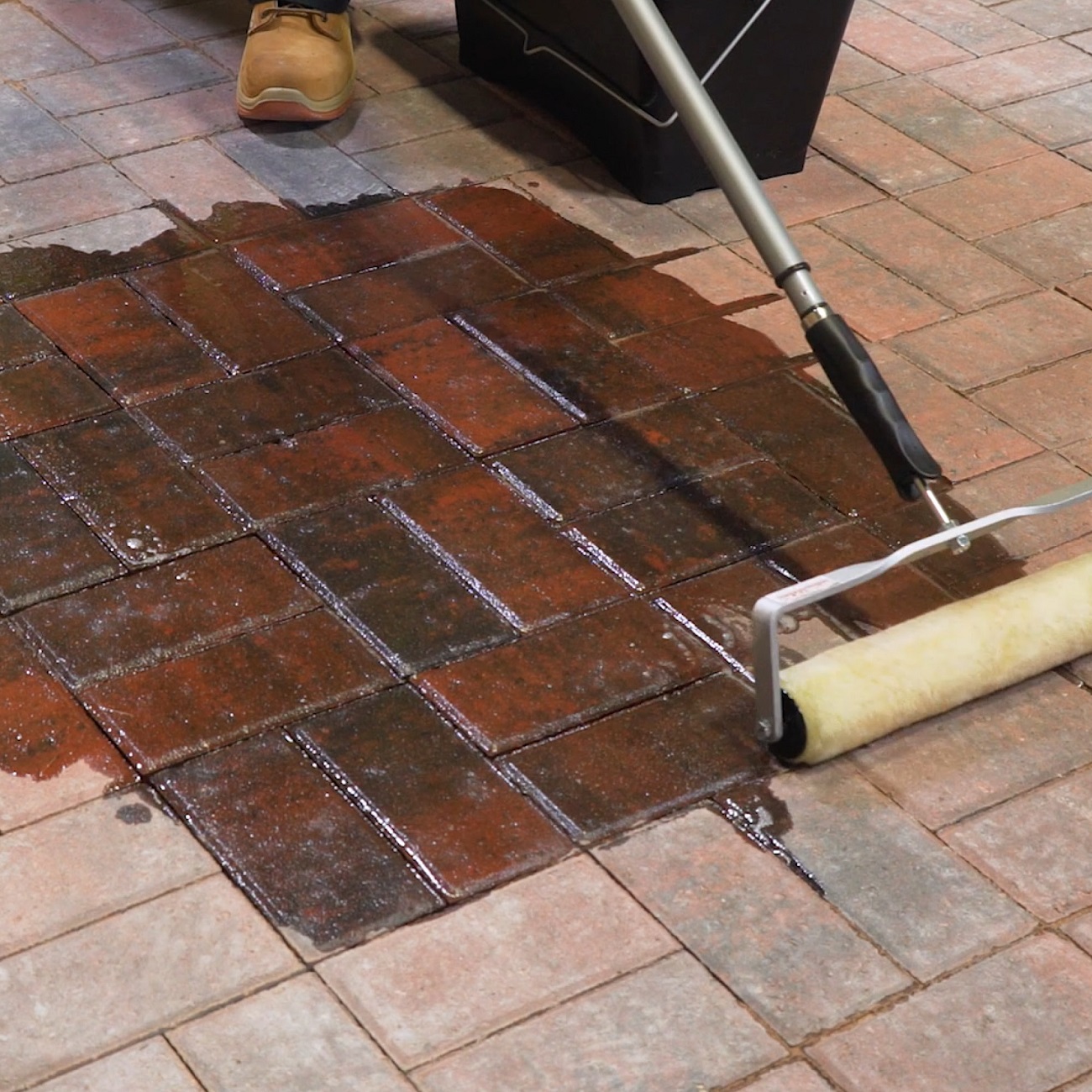 Application of block paving sealer with a roller on brick paving.