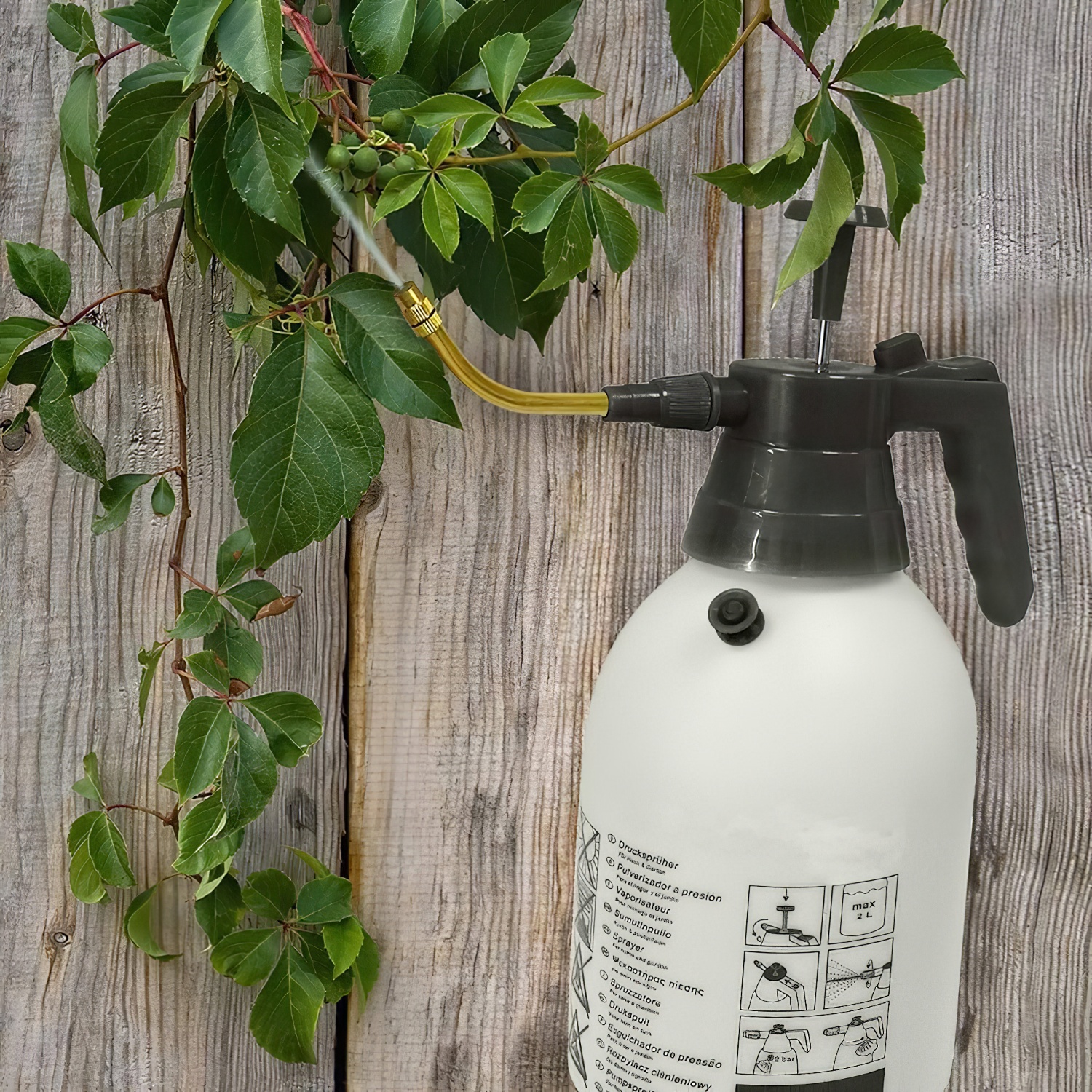 Faithfull 2L garden hand held pump pressure sprayer with ergonomic handle and adjustable nozzle, shown with additional nozzle attachment.- in use with flexible nozzle