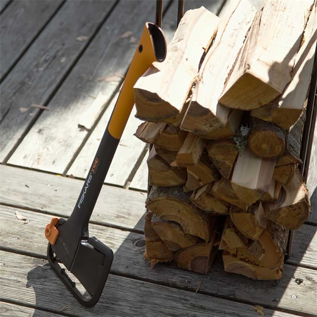 Fiskars axe leaning against a stack of chopped wood on a wooden deck.