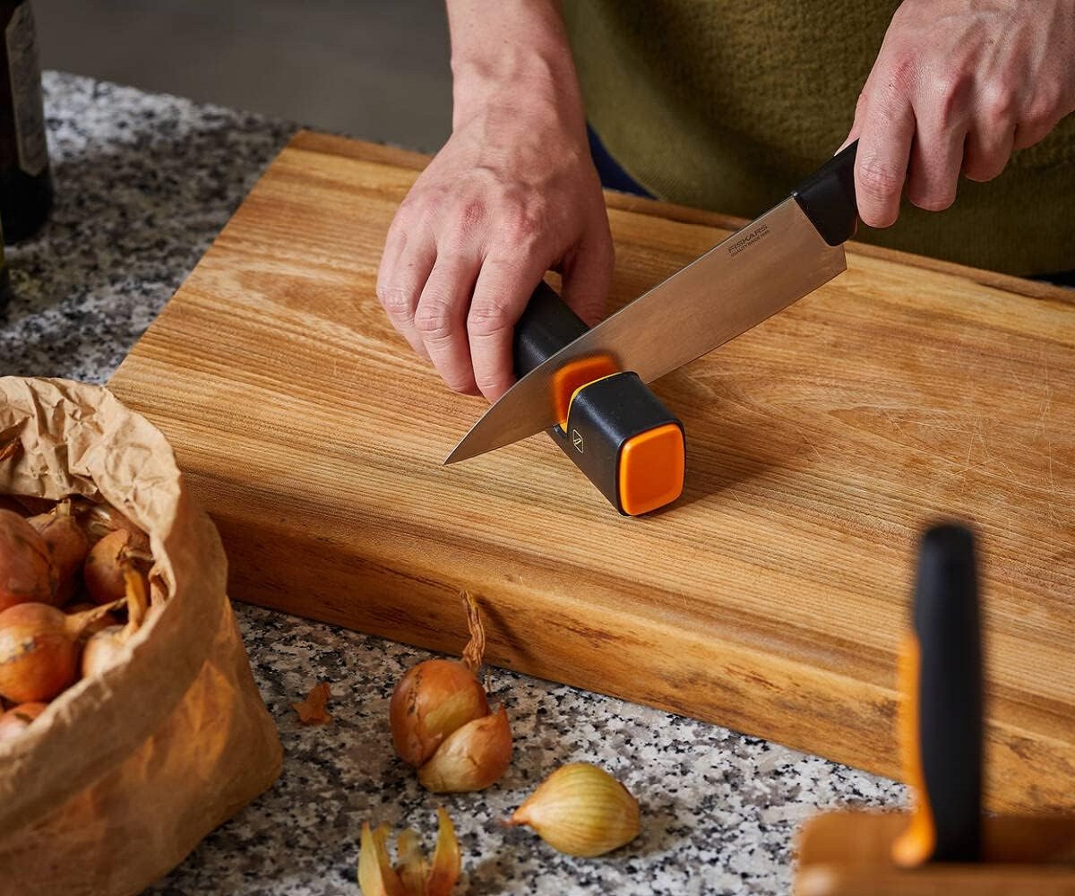 side vies sharpening a kitchen knife Fiskars knife sharpener with black and orange design
