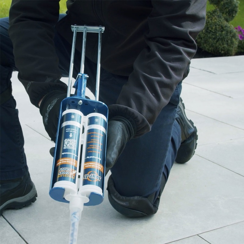 Person using a mixing nozzle with Joint It Porcelain Epoxy Grout Twin Pack on outdoor tiles.