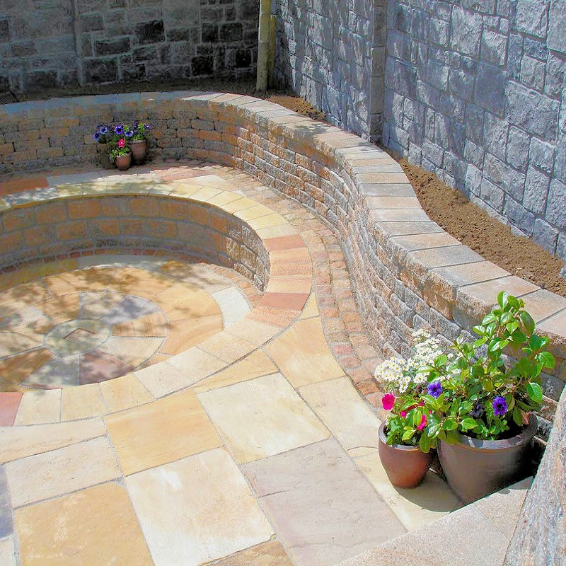Natural stone patio with curved seating area and potted plants.