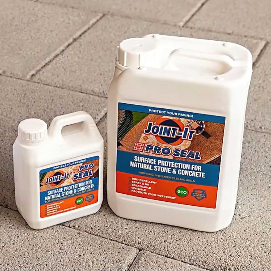 Two containers of Joint It Pro Seal Weatherproofing Sealer for Paving and Stone placed on a paved surface.