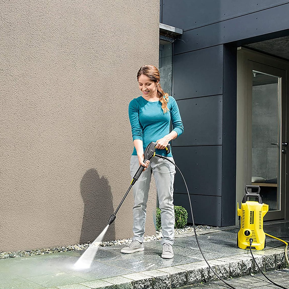 Person using a Karcher pressure washer on a patio.