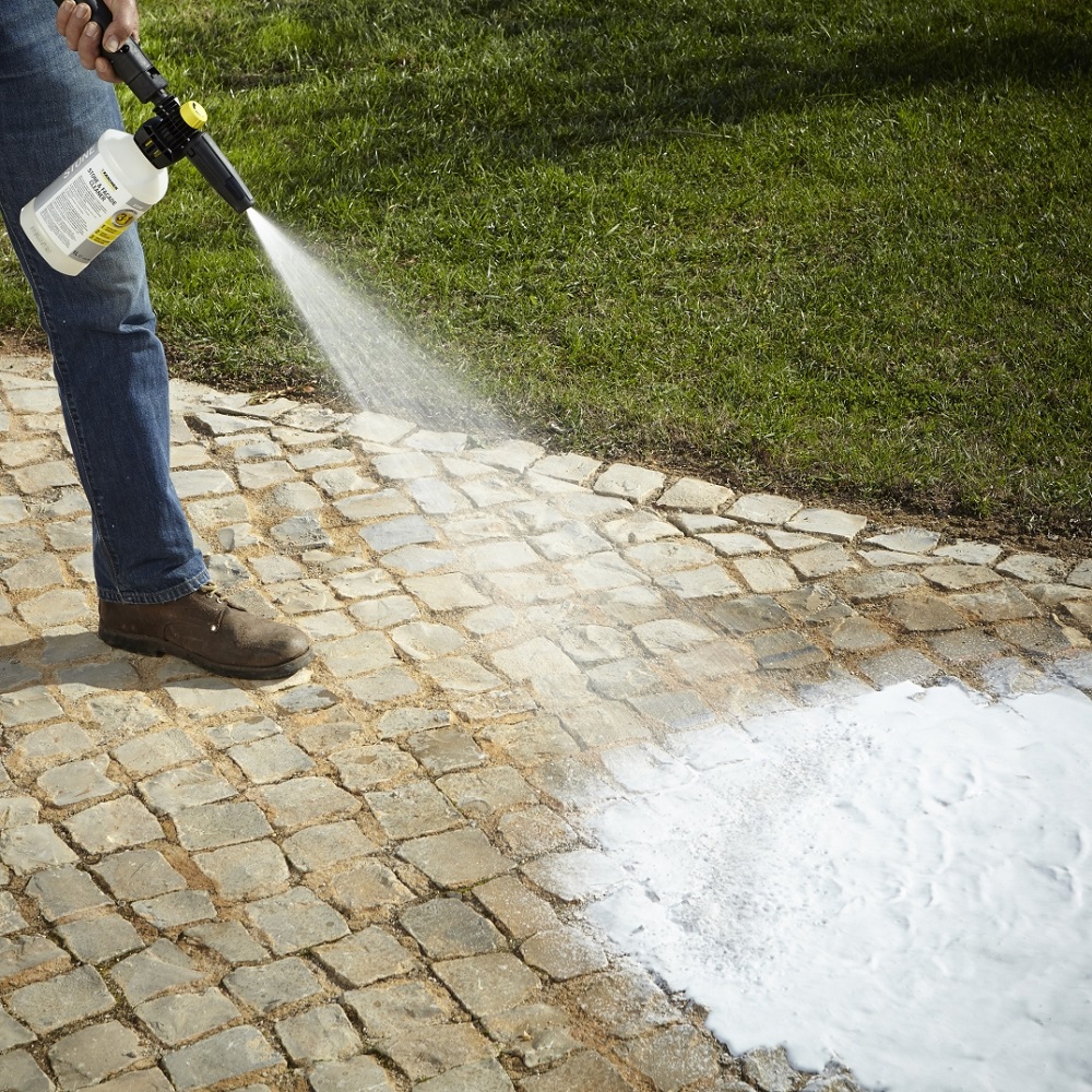 Person using Karcher Stone Path, Patio and Facade Cleaner Liquid Concentrate on a stone path.