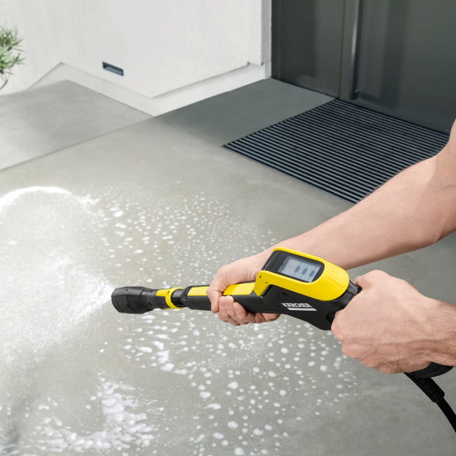 Person using a pressure washer to clean a concrete surface with foam.
