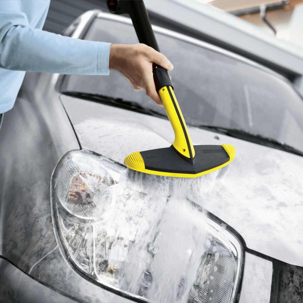 Person using Karcher soft brush pressure washer on car headlight for gentle cleaning