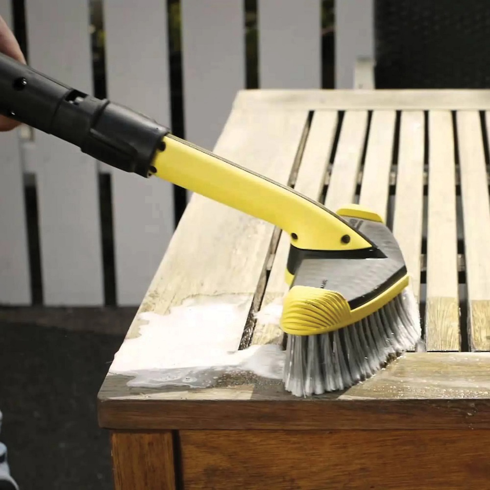 Karcher soft brush pressure washer cleaning a wooden surface with soap suds visible.
