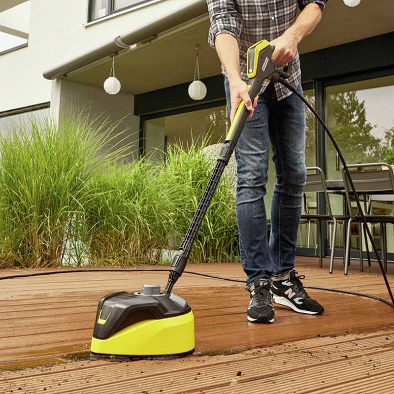 Person using a Karcher pressure washer on a wooden deck.