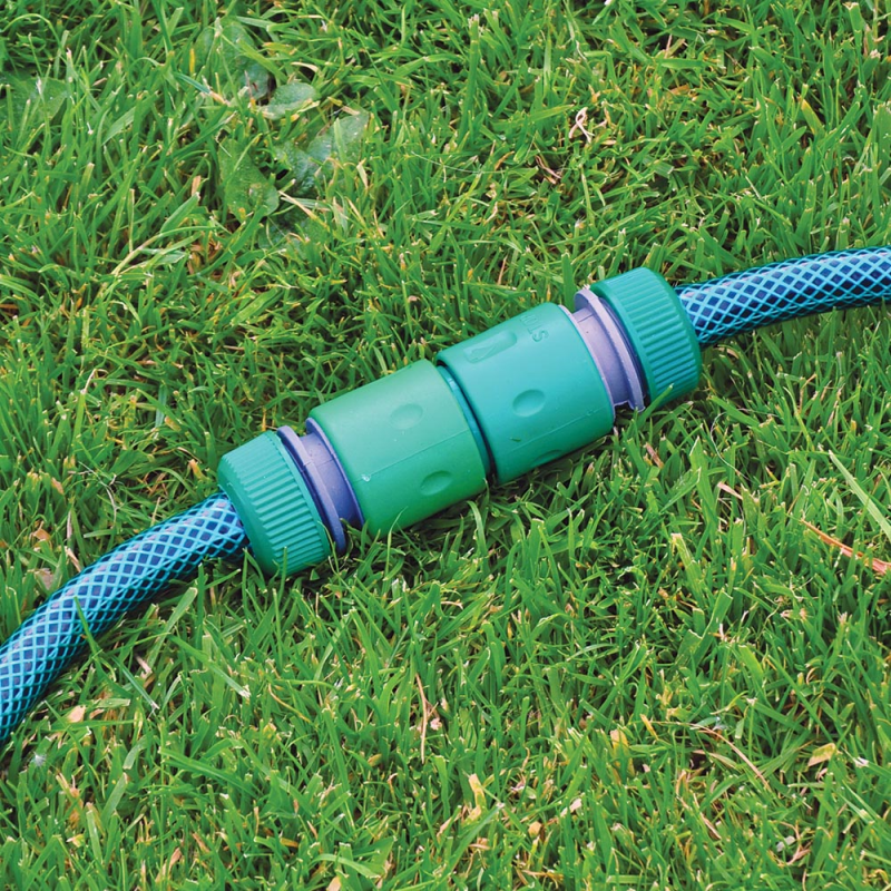 Green and blue garden hose with male adapter on grass