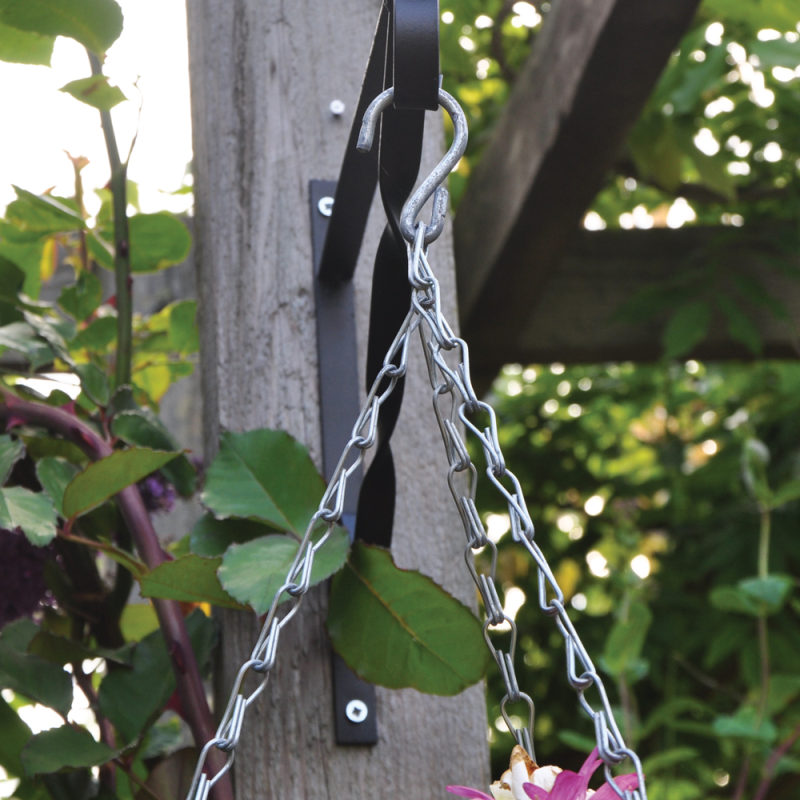 Galvanised hanging basket chain attached to a wooden post in a garden setting.