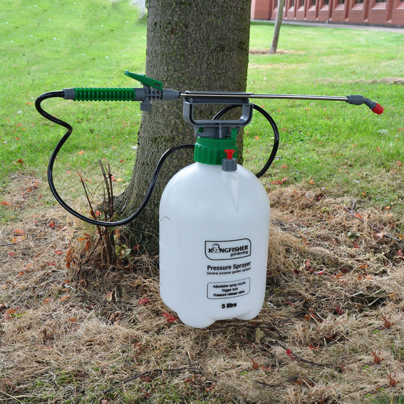 Kingfisher Garden 5L Pump Action Pressure Sprayer placed on grass next to a tree.