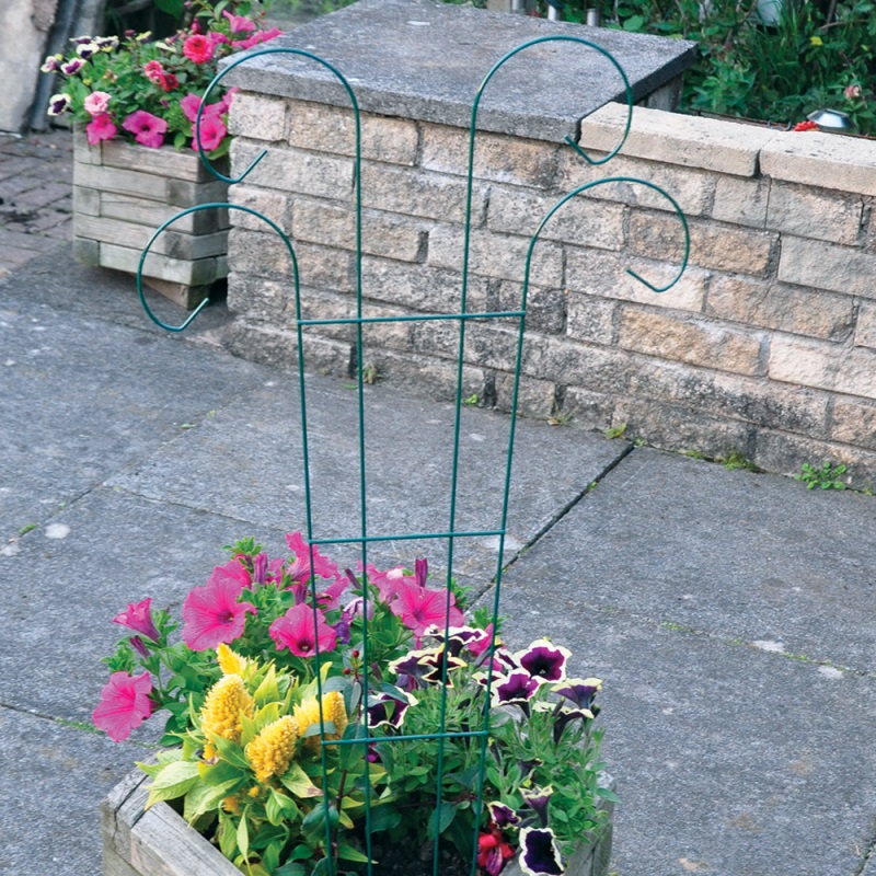 Metal plant support in a garden with colourful flowers.