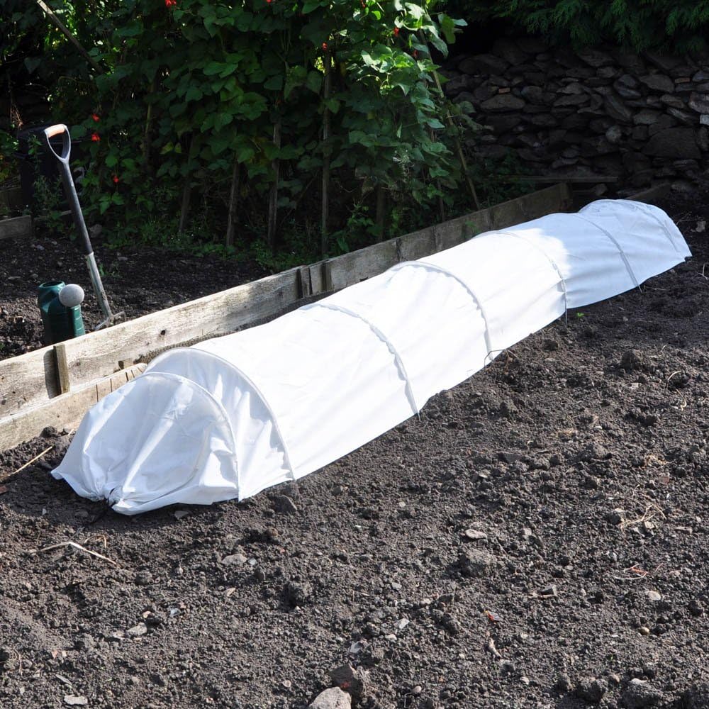 White fleece grow tunnel in a garden setting for frost protection.