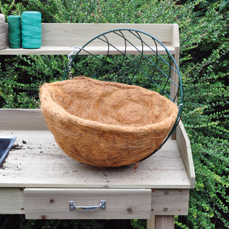 Round flower hanging basket with coco liner placed on a wooden garden bench.