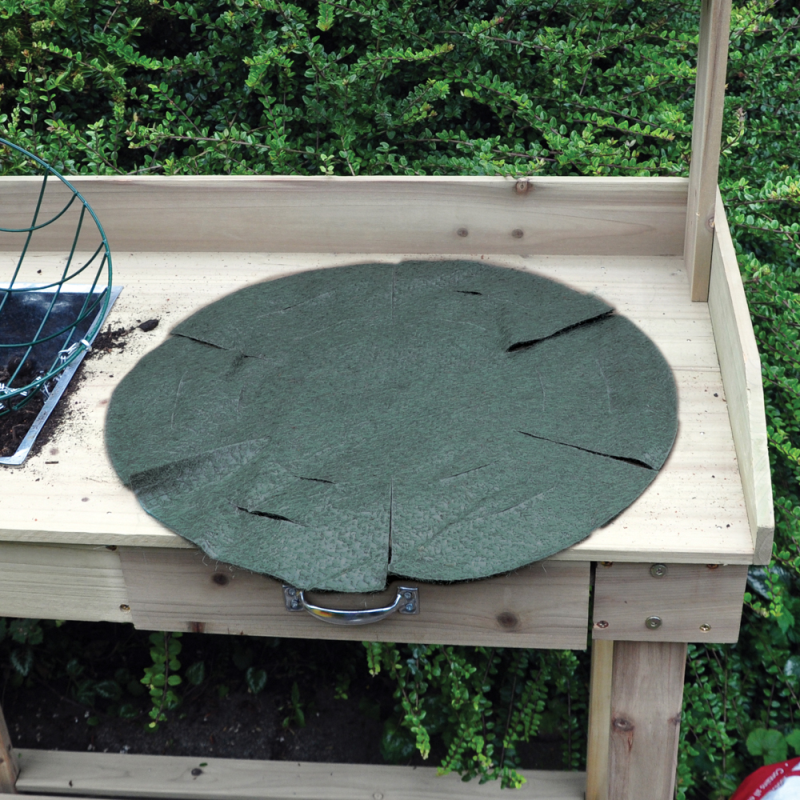 Green jute liner for a 16-inch round hanging basket placed on a wooden table with greenery in the background.