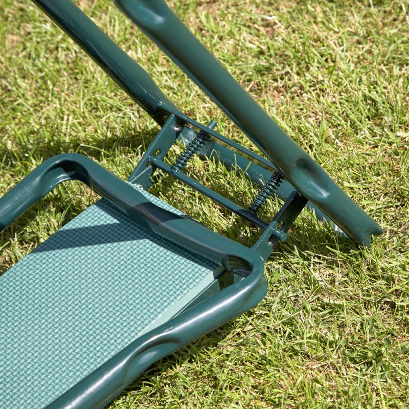 Close-up of a green garden kneeler with handles and seat on grass.