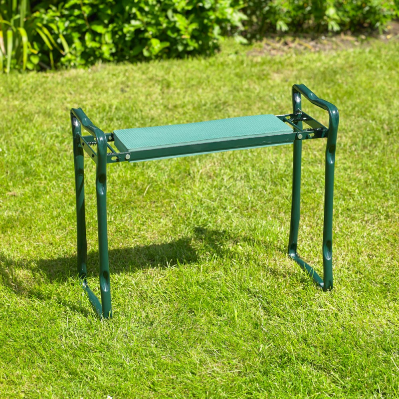 Green garden kneeler with handles on grass.