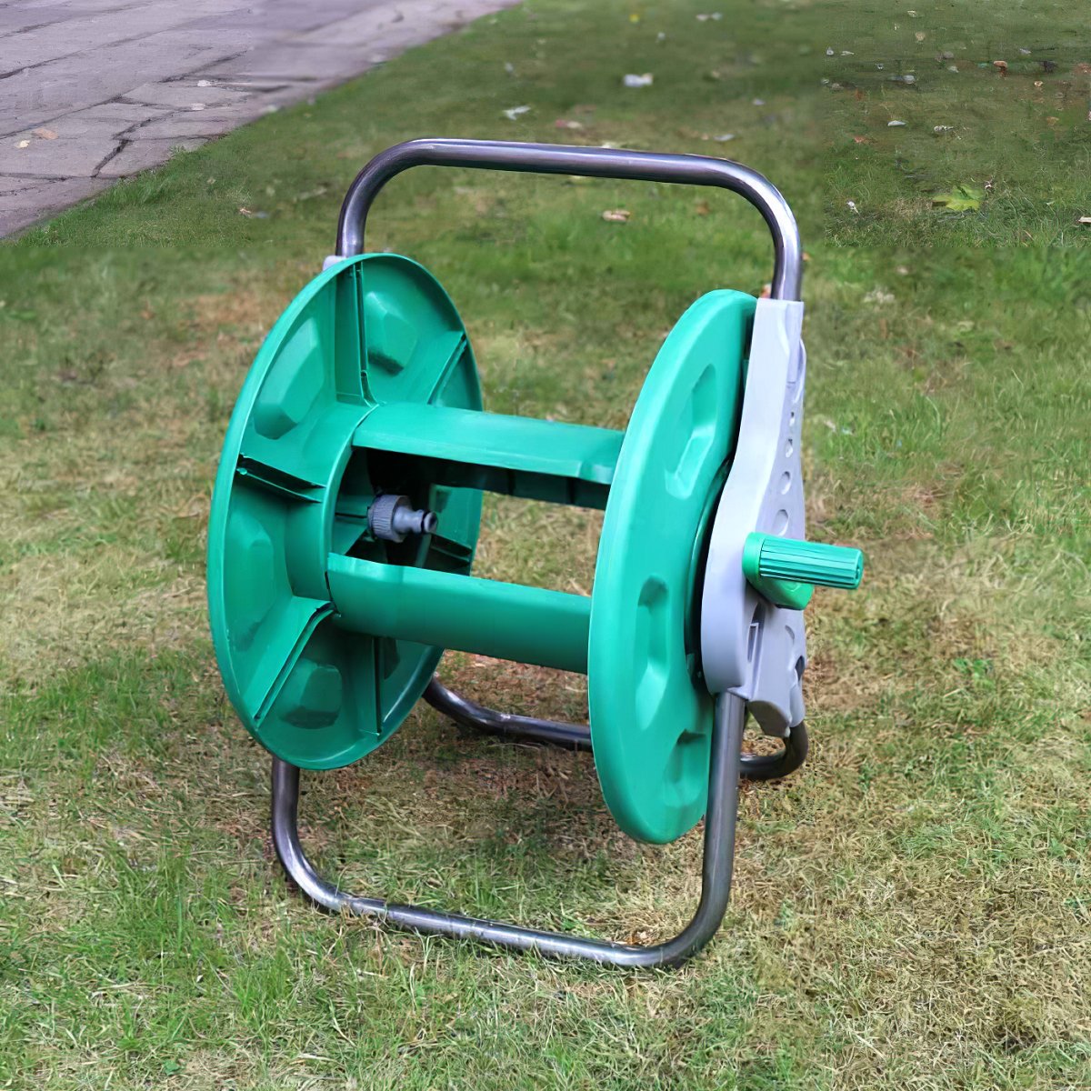 Green and silver free standing garden hose reel on grass.
