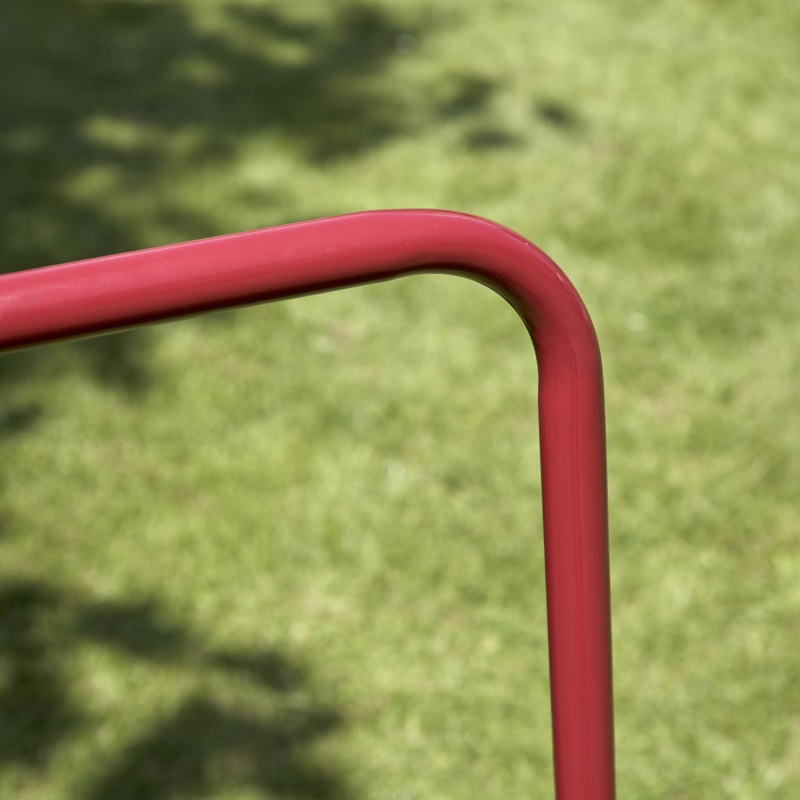 Close-up of a red metal handle against a grassy background.
