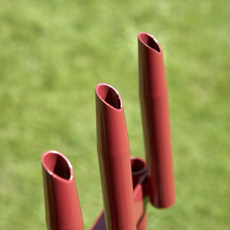 Close-up of the prongs on a lawn aerator plug cutter against a grassy background.