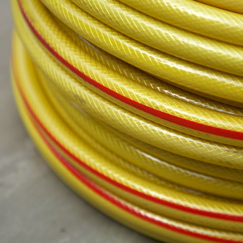 Close-up of a coiled yellow hose pipe with a red line.